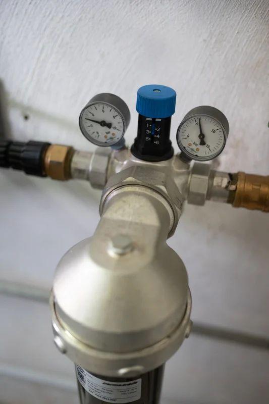 Ein Wasserfilter mit Druckregler und zwei Manometern ist in einer Rohrleitung installiert.